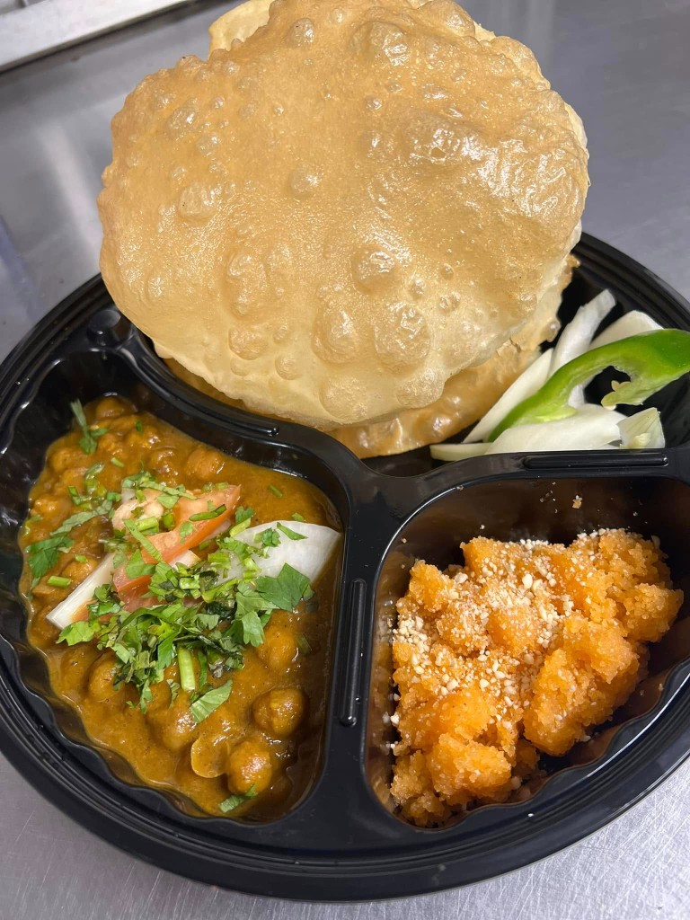 Chole bhature platter with chickpea curry, gajar halwa, and fresh salad