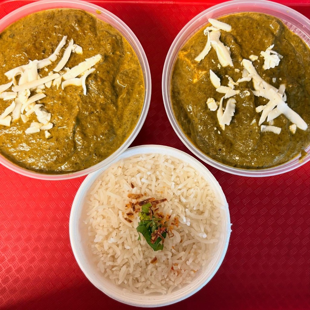 Two bowls of creamy saag paneer topped with fresh cheese and basmati rice